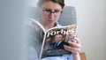 Woman reading newspaper Forbes top billionaires list