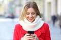 Woman reading phone messages in the street in winter