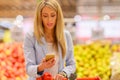 Woman reading shopping list on her phone while shopping in supermarket Royalty Free Stock Photo
