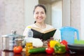 Woman reads cookbook for recipe at kitchen Royalty Free Stock Photo