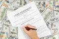 A woman reads and signs a loan agreement on the background of dollar bills Royalty Free Stock Photo