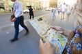 A woman reads a tourist street map on the sidewalk in Rome, Italy