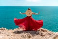 A woman, rear view in a red flying dress fluttering in the wind, a girl in a fluttering dress on the background of the Royalty Free Stock Photo