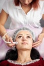 Woman receiving electric ultrusound facial massage at beauty salon