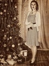 Woman receiving gifts under Christmas tree. Old photo yellow paper. Royalty Free Stock Photo