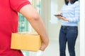 Woman receiving package and signing on digital tablet from delivery man. Royalty Free Stock Photo