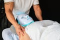 Woman receiving a massage while wearing blue led light phototherapy facial mask. Royalty Free Stock Photo