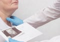 A woman is on reception at the endocrinologist, the doctor looks at the results of an ultrasound scan of the thyroid gland, close-