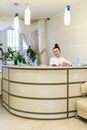 Woman receptionist in medical coat stands at reception desk