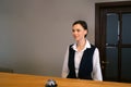 Woman receptionist on reception at the hotel with a bell on a wooden table. Royalty Free Stock Photo