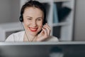 Woman receptionist wear headset consulting customer looking at computer talking with client in online computer chat Royalty Free Stock Photo