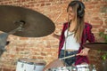 Woman recording music, singing and playing drums while sitting in loft workplace or at home