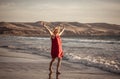 Woman in red with arms outstretched by the sea at sunrise enjoying freedom and outdoors life Royalty Free Stock Photo