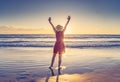 Woman in red with arms outstretched by the sea at sunrise enjoying freedom and outdoors life Royalty Free Stock Photo