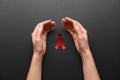 Woman with red awareness ribbon on black background, top view. World AIDS disease day Royalty Free Stock Photo