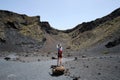Woman with red backpack photographing from inside the crater of El cuervo volcano, Lanzarote. Royalty Free Stock Photo