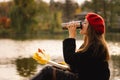 Woman in a red beret reading book on wooden pontoon. Autumn season. Royalty Free Stock Photo