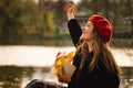 Woman in a red beret reading book on wooden pontoon. Autumn season. Royalty Free Stock Photo