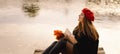 Woman in a red beret reading book on wooden pontoon. Autumn season. Royalty Free Stock Photo