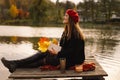 Woman in a red beret reading book on wooden pontoon. Autumn season. Royalty Free Stock Photo