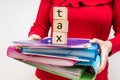 A woman in a red blouse is holding a stack of document folders and pads with the words Tax, Taxes and billing, paperwork concept Royalty Free Stock Photo