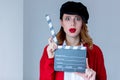 Woman in red cardigan and hat with clapboard Royalty Free Stock Photo