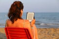 Woman on red chair reads the ebook on the beach Royalty Free Stock Photo