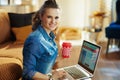 Woman with red coffee cup and online travel site on laptop
