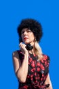 Woman in red dress and black hat with retro black phone on blue background Royalty Free Stock Photo