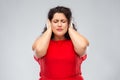 Woman in red dress closing her ears by hands