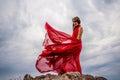 Woman in red dress dance over storm sky, gown fluttering fabric flying as splash Royalty Free Stock Photo