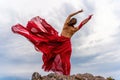 Woman in red dress dance over storm sky, gown fluttering fabric flying as splash Royalty Free Stock Photo