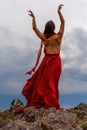 Woman in red dress dance over storm sky, gown fluttering fabric flying as splash Royalty Free Stock Photo