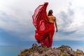 Woman in red dress dance over storm sky, gown fluttering fabric flying as splash Royalty Free Stock Photo