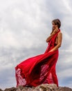 Woman in red dress dance over storm sky, gown fluttering fabric flying as splash Royalty Free Stock Photo