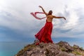 Woman in red dress dance over storm sky, gown fluttering fabric flying as splash Royalty Free Stock Photo