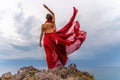 Woman in red dress dance over storm sky, gown fluttering fabric flying as splash Royalty Free Stock Photo