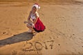Woman in red dress with drawing on the sand digits 2017 Royalty Free Stock Photo