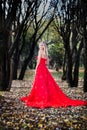 Woman in red dress in fall fairy tale forest. Autumn Royalty Free Stock Photo