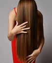 Woman in red dress has tilted haed forward and brushes run fingers through her long silky straight hair covering face Royalty Free Stock Photo