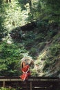 A woman in a red dress and hat, sitting on the landing with her legs dangling, and smiling looks into up. Vertical. Travel concept