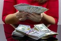 Woman in red dress holdind and counting cash money american dollars in her hands on black table background Royalty Free Stock Photo