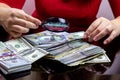 Woman in red dress holdind and counting cash money american dollars in her hands on black table background Royalty Free Stock Photo