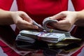 Woman in red dress holdind and counting cash money american dollars in her hands on black table background Royalty Free Stock Photo