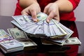 Woman in red dress holding and counting cash money american dollars in her hands on black table background. Profit and reward Royalty Free Stock Photo