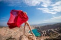 woman red dress lake mountains. Side view of a woman in a long red dress posing on a rock high above the lake. Against Royalty Free Stock Photo