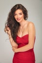 Woman in red dress posing while fixing her long hair Royalty Free Stock Photo