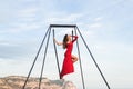 Woman in red dress practicing pole fly dance poses in a hammock outdoor Royalty Free Stock Photo