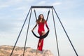 Woman in red dress practicing pole fly dance poses in a hammock outdoor Royalty Free Stock Photo
