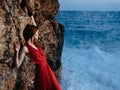 Woman in red dress rocky stone landscape ocean waves Royalty Free Stock Photo